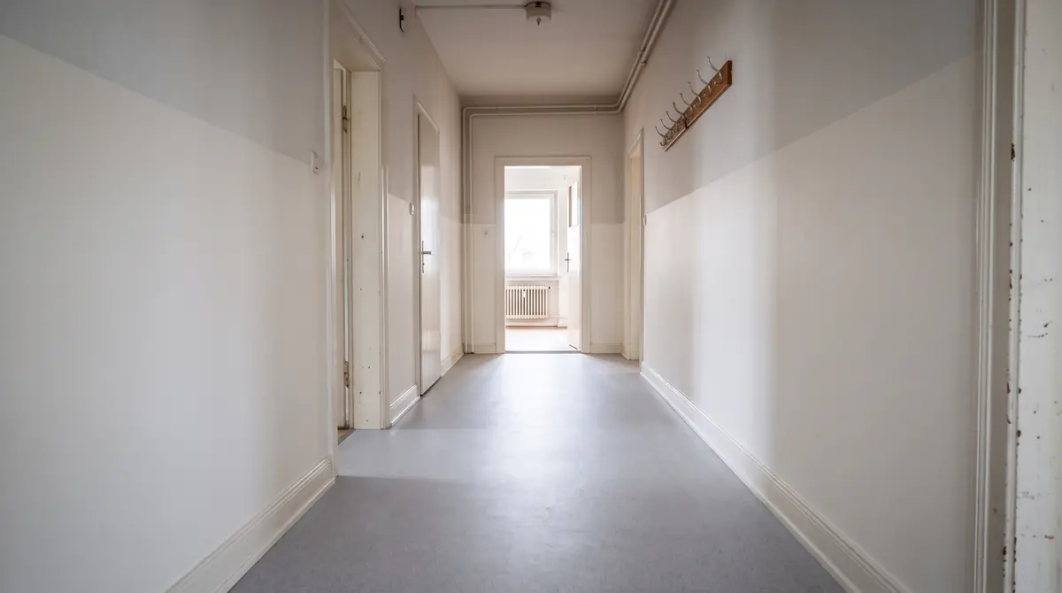 Derselbe Flur mit neuem hellem Bodenbelag und sauberer Wand